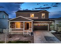 Charming two-story home with a stone facade and inviting front porch at dusk at 5256 Trails Edge Ln, Castle Rock, CO 80104
