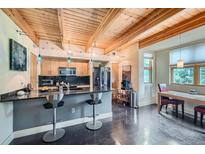 Open kitchen with wood ceiling beams, island with bar stools, and modern appliances at 801 Confidence Dr # 16, Longmont, CO 80504