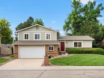 Two-story home featuring a red front door, attached two car garage, and a well-manicured front lawn at 13762 W 67Th Pl, Arvada, CO 80004