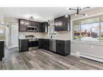 A well-lit kitchen features stainless steel appliances, granite countertops and hardwood floors at 6913 Teller Ct, Arvada, CO 80003