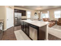Stylish kitchen boasts dark cabinets, stainless steel appliances, and a large island with seating at 19468 E 65Th Pl, Aurora, CO 80019