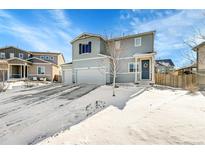 Two-story house with gray siding, attached garage, and snowy front yard at 533 Pioneer Ct, Fort Lupton, CO 80621