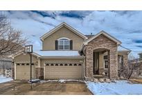 Charming two-story home showcasing a 3-car garage, stone accents, and a welcoming covered entryway at 14096 Roaring Fork Cir, Broomfield, CO 80023