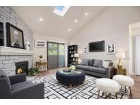Bright living room features a stone fireplace, vaulted ceilings with skylight, and modern furnishings at 10150 E Virginia Ave # 7-304, Denver, CO 80247