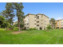 Well-maintained condo building with lush green lawn and mature shade trees on a clear, sunny day at 9625 E Center Ave # 5C, Denver, CO 80247