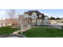 Two-story house with stone facade, landscaped lawn, and walkway at 9965 E 143Rd Way, Brighton, CO 80602