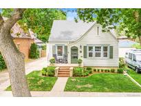 Charming bungalow featuring a well-manicured front yard with landscaped flower beds, a brick entryway, and a cozy front porch at 821 Collyer St, Longmont, CO 80501