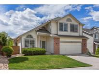 Charming two-story home featuring a well-manicured lawn, brick accents, and an attached two-car garage at 8985 Edgewood Ln, Highlands Ranch, CO 80130