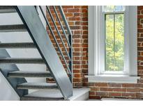 Interior staircase featuring a metal railing and a brick wall with a window at 2193 Arapahoe St # 15, Denver, CO 80205