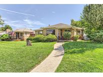 Charming brick home with a well-manicured lawn and walkway leading to the front door on a sunny day at 3550 Holly St, Denver, CO 80207