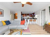Bright living room with a gray couch, colorful pillows, and an open view to the kitchen at 1150 Vine St # 306, Denver, CO 80206