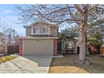 Two story home with a two car garage, brick accents, neutral color, and mature landscaping at 15921 Bluebonnet Dr, Parker, CO 80134
