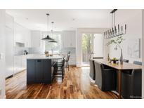 Bright, modern kitchen featuring white cabinets, wood floors, and center island with marble countertops at 3130 Wyandot St, Denver, CO 80211