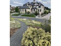 Stunning stone home with a manicured lawn, lush landscaping, and a grand entrance at 10704 Flowerburst Ct, Highlands Ranch, CO 80126