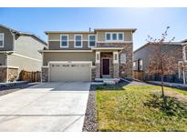 Charming two-story home with stone accents, a two-car garage, and a well-maintained front lawn at 9334 Sedalia St, Commerce City, CO 80022