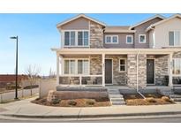 Charming two-story townhome featuring a covered front porch and stone accents for added curb appeal at 8811 Meade St, Westminster, CO 80031