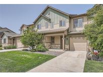 Two-story townhouse with a covered porch, a two-car garage, and a well-maintained lawn at 3573 S Lisbon Ct, Aurora, CO 80013