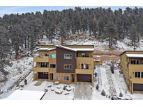 Modern townhouse featuring multi-tone exteriors, private balconies, and attached garages nestled against a snowy wooded backdrop at 726 Dreamcatcher Ln, Evergreen, CO 80439