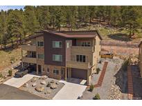Modern three-story townhouse with attached garages, balconies, and native landscaping in a wooded neighborhood at 726 Dreamcatcher Ln, Evergreen, CO 80439