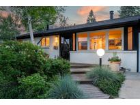 Charming single-story home with brick exterior, inviting entry, manicured landscaping, and warm exterior lighting at 7121 E Arkansas Ave, Denver, CO 80224