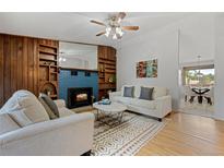 Inviting living room featuring a fireplace with painted brick, wood built-ins, and a cozy seating area at 7563 Lamar Ct, Arvada, CO 80003