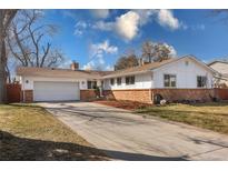 Charming single-story home featuring a brick facade, attached garage, and a well-maintained lawn with a long driveway at 7629 S Cedar Cir, Littleton, CO 80120