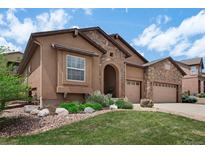 Inviting stucco home featuring stone accents, arched entryway, three-car garage, and landscaped front yard at 15616 Soo Line Way, Monument, CO 80132