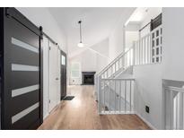 Bright foyer with hardwood floors, black sliding doors, white stairway and fireplace in the background at 772 Ivywood Ct, Highlands Ranch, CO 80126