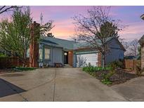 Charming single-Gathering home featuring a brick chimney, attached garage, and lush trees under a vibrant sunset at 772 Ivywood Ct, Highlands Ranch, CO 80126