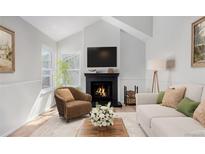 Cozy living room features a fireplace with black tile surround, plush furniture, and light wood flooring at 772 Ivywood Ct, Highlands Ranch, CO 80126