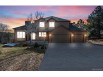 Inviting two-story home boasts a spacious driveway and a beautifully landscaped front yard beneath a colorful sunset at 6374 Arapahoe Ct, Parker, CO 80134