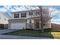 Two-story home featuring a brick and siding exterior, attached two-car garage, and a well-manicured front lawn at 13684 Lilac St, Thornton, CO 80602