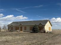 Single-story home with weathered exterior, set against a blue sky with scattered clouds at 5500 Dacono Ct, Byers, CO 80103