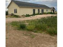 Sprawling single-story home with a detached garage on a large, overgrown lot at 5500 Dacono Ct, Byers, CO 80103