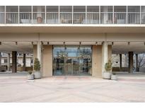 Modern building entrance featuring glass doors, brick accents, and decorative planters at 1201 N Williams St # 16A, Denver, CO 80218