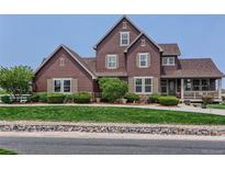 Charming two-story home featuring a manicured lawn, inviting front porch, and classic architectural details at 12745 Uinta St, Brighton, CO 80602