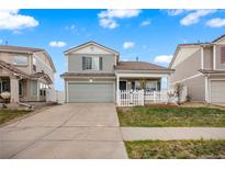 Charming two-story home with a well-manicured lawn and a quaint front porch with a white picket fence at 20414 E 55Th Pl, Denver, CO 80249