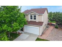Two-story home with tan siding, new brown shingle roof and well-maintained landscaping at 7270 Marmot Ridge Pl, Littleton, CO 80125