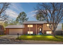 Charming brick home featuring a well-maintained lawn, mature trees, and an attached two-car garage at 10429 Quivas St, Northglenn, CO 80234