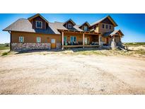 Beautifully crafted exterior with stone accents and a covered porch, showcasing rustic charm and inviting curb appeal at 2710 Rustlers Canyon Loop, Elizabeth, CO 80107
