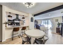 Bright open-concept living and dining area with modern kitchen and light-filled living room with sliding door at 12131 Melody Dr # 201, Denver, CO 80234