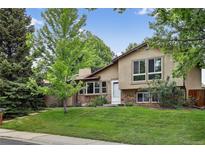 Inviting exterior showcasing a well-maintained lawn and charming stone accents, with abundant mature trees for shade at 18445 W 59Th Dr, Golden, CO 80403
