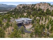 Stunning luxury home with mountain views surrounded by lush trees and unique rock formations at 6767 Timbers Dr, Evergreen, CO 80439