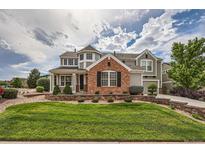 Beautiful two story home with brick and siding and manicured front lawn and garden at 8469 Winter Berry Dr, Castle Pines, CO 80108