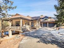 A luxurious residence boasts a three-car garage and an inviting covered porch with stone supports and detailed wood railing at 1374 Crested Butte Ct, Evergreen, CO 80439