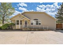 Tan home with a ramp leading to the front door and large concrete driveway at 8843 W Phillips Dr, Littleton, CO 80128