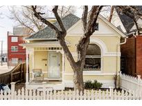 Charming yellow brick home featuring a welcoming porch, white picket fence, and beautiful architectural details at 2909 Glenarm Pl, Denver, CO 80205