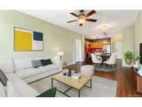 Open-concept living room with hardwood floors, ceiling fan, and comfortable seating area at 9633 E 5Th Ave # 10208, Denver, CO 80230