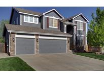 Two-story home with a three car garage, stone accents, and mature lawn at 331 Las Lomas St, Brighton, CO 80601