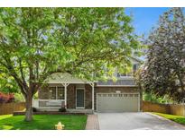 Charming two-story home featuring a stone facade, covered porch, and well-maintained front lawn and a two car garage at 14794 Vine St, Thornton, CO 80602